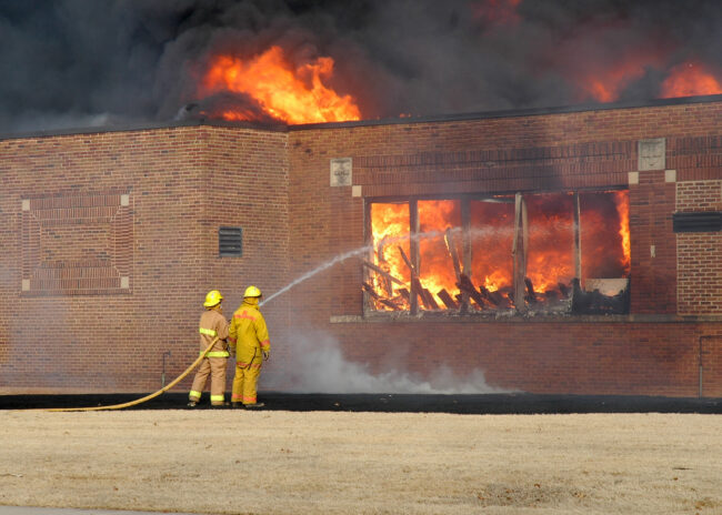 Public education is facing a five-alarm fire. Photo depicting firefighters working a fire in an empty, school building.